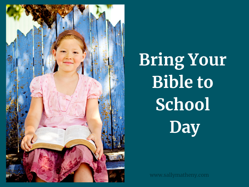 Young, smiling girl holding Bible. Text: Bring Your Bible To School Day