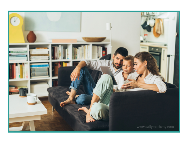 Shows a mom and dad sitting on a sofa talking with their young son.