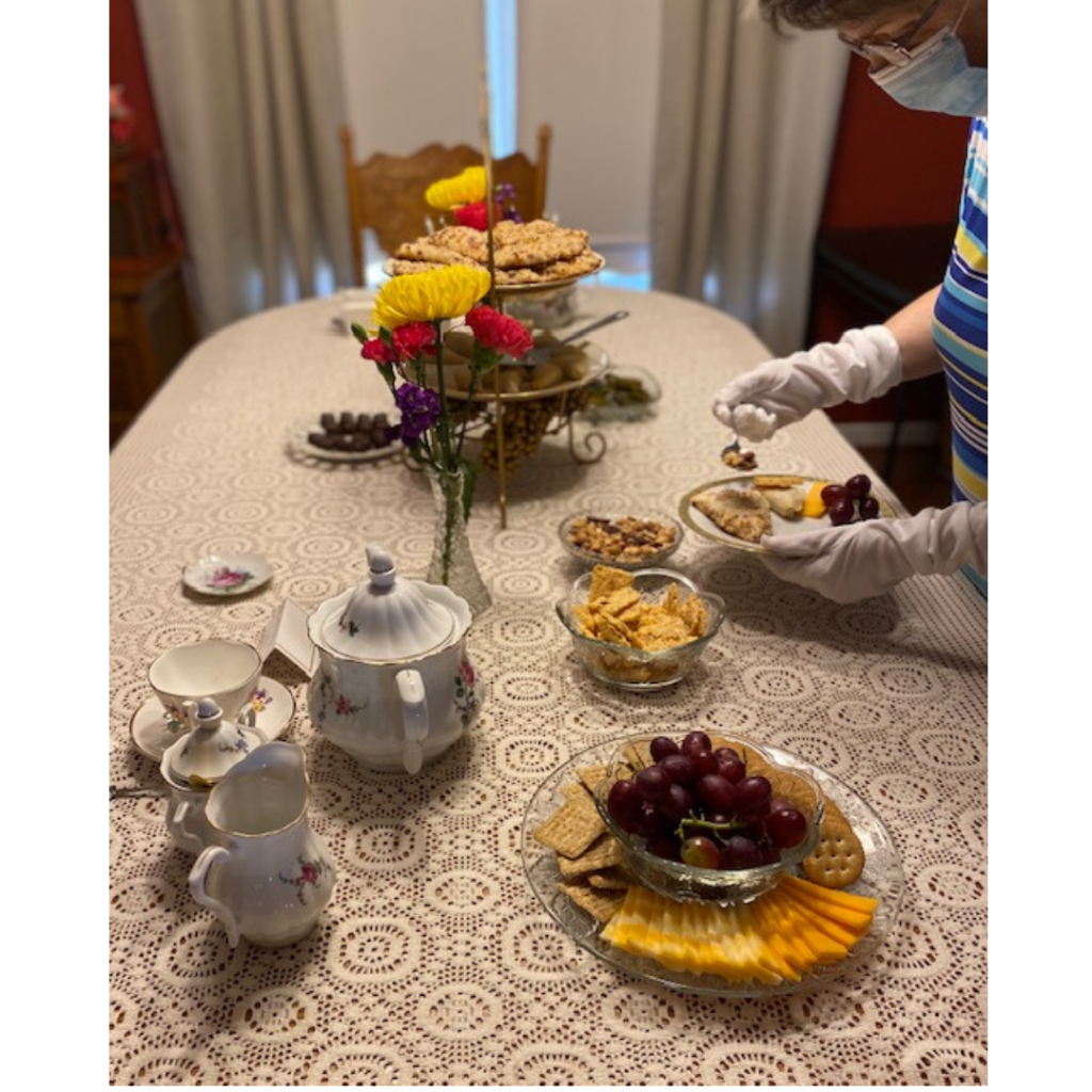 Having a tea social wearing white gloves and a mask.