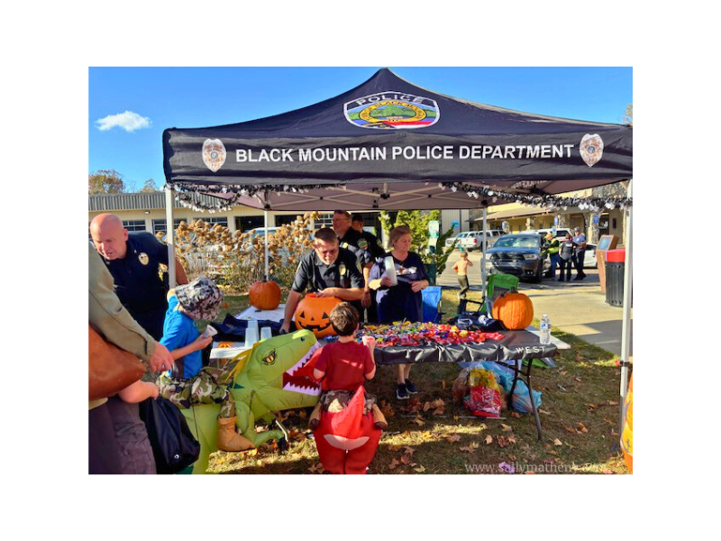 Black Mountain Police handing out candy to children in Halloween costumes.